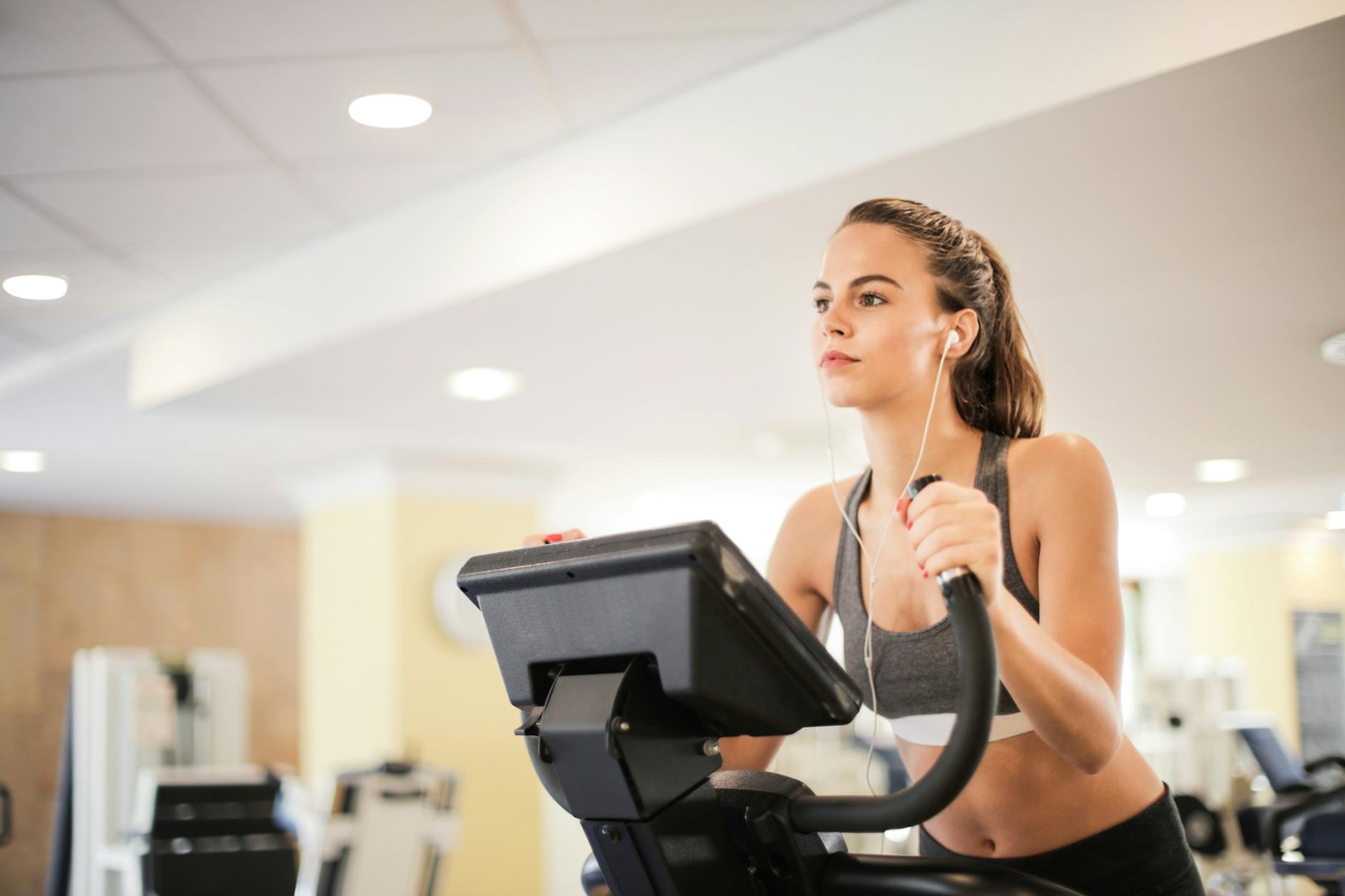 Kobieta na siłowni ćwiczy na orbitreku podczas treningu cardio