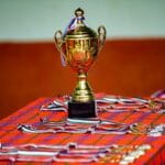 Jak dobrać statuetki na firmową galę, by zachwycić laureatów Złote trofeum z medalami i wstążkami na kraciastej powierzchni